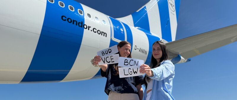 2 Frauen stehen vor einem weiß-blau gestreiften Flieger von Condor und alten 4 Zettel in der Hand, auf denen LGW, BUD, BCN und VCE steht 