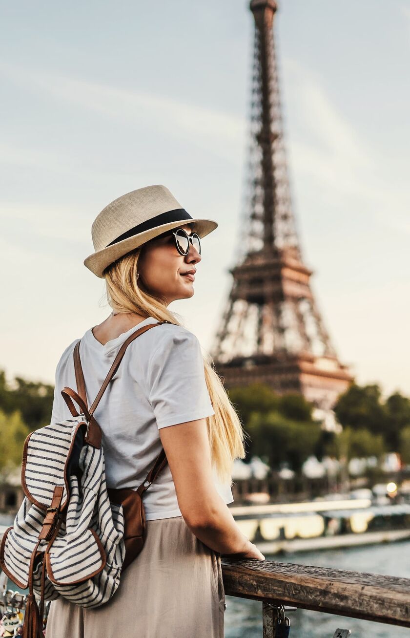 Frau mit Hut schaut auf den Pariser Eifelturm