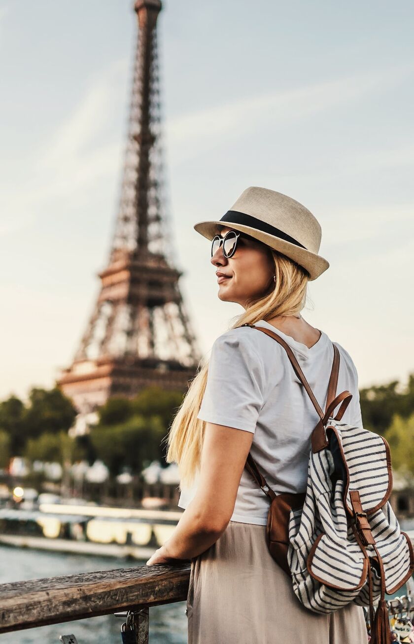 Frau mit Hut schaut auf den Pariser Eifelturm