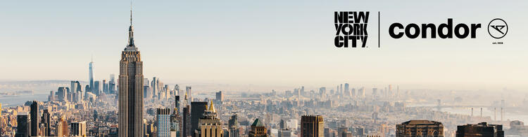 Skyline von Manhattan im Sonnenlicht mit dem Empire State Building im Vordergrund und dem One World Trade Center im Hintergrund