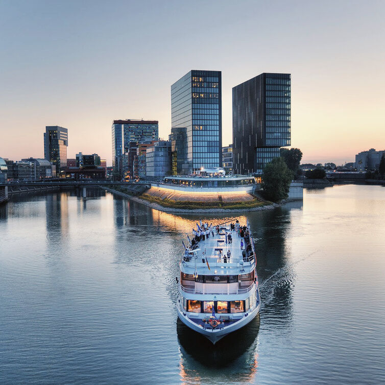 Ein Boot auf dem Rhein in Düsseldorf mit Hochhäusern im Hintergrund
