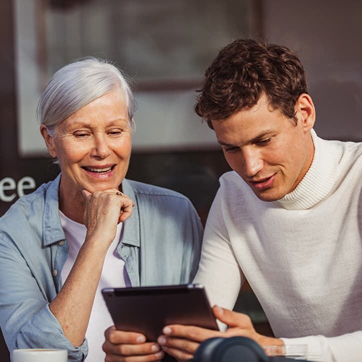 Frau und Mann sitzen im Cafe und schauen auf ein Tablet