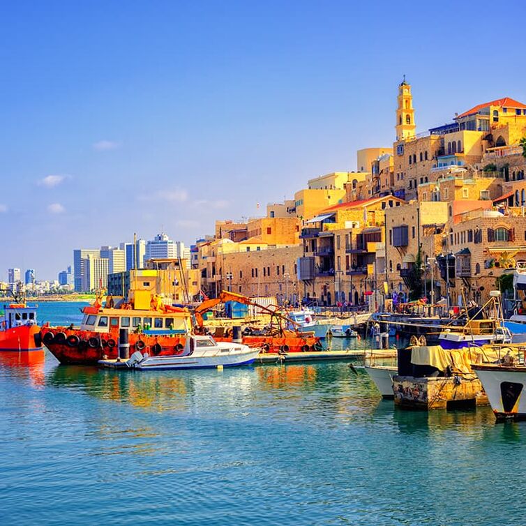 Blick auf Tel Aviv mit bunten Booten vom Wasser aus.