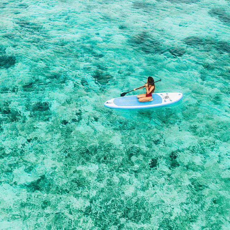 Frau sitzt auf der sup Board und genießen türkis transparent Wasser in tropischen Saphirglas klaren ruhigen Wasser.