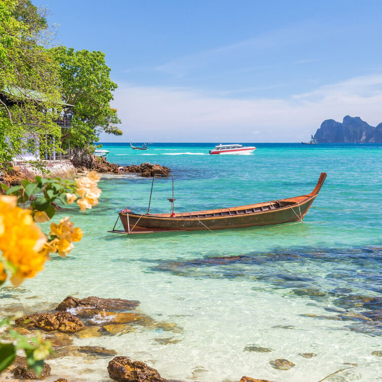 Ein Strand mit einem Boot im Vordergrund und türkisblauem Wasser im Hintergrund