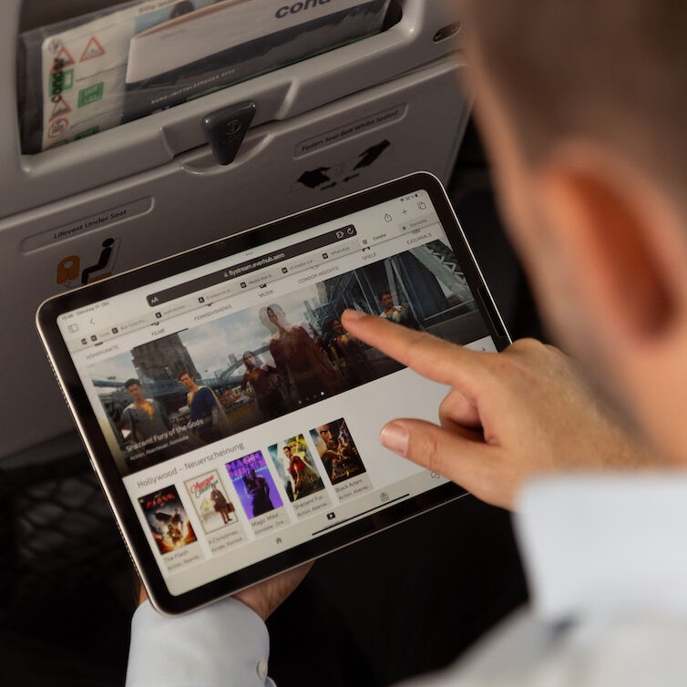 Zwei Passagiere an Bord eines Flugzeugs verbinden ihr iPad mit Condor Flystream
