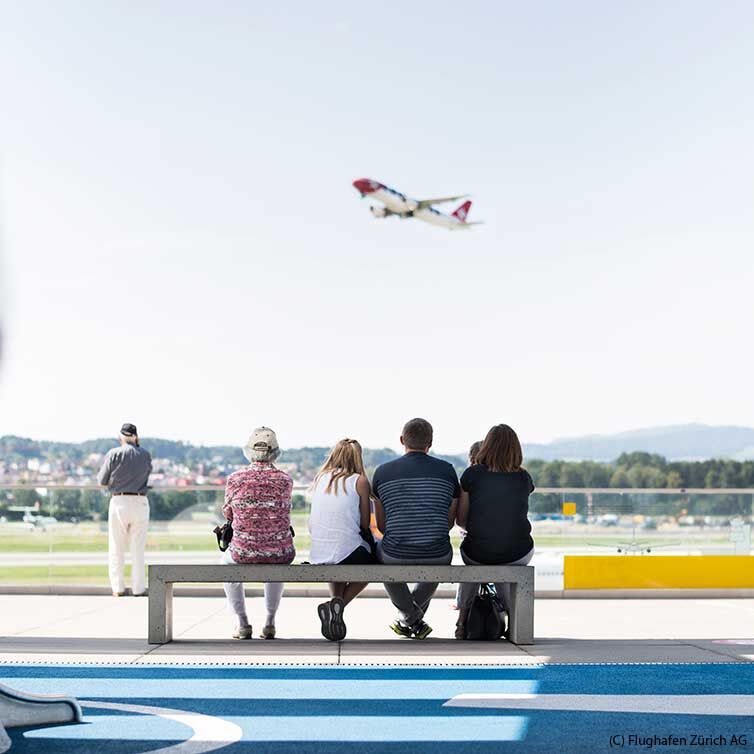 Zuschauer sitzen auf der Bank und beobachten die Flugzeuge