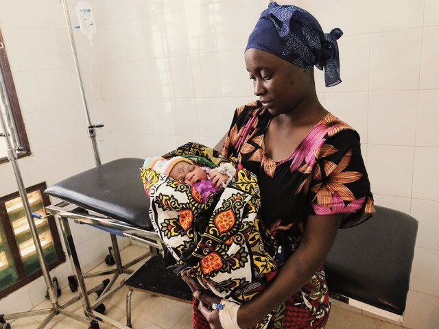 Mutter mit Baby im Arm auf einer Krankenstation. 