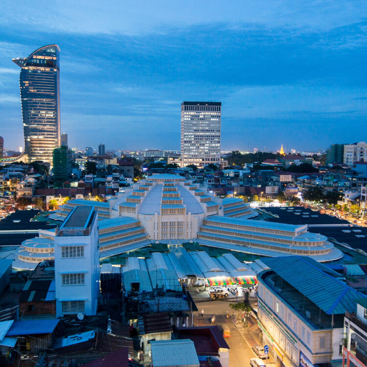 Der beleuchtete Zentralmarkt Phsar Thmei in Phnom Penh bei Dämmerung mit seinem markanten Kuppeldach in Art-Déco-Stil.