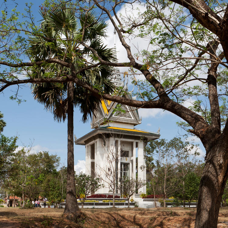 Weiße Gedenkstupa in Choeung Ek bei Phnom Penh, eingerahmt von Bäumen.