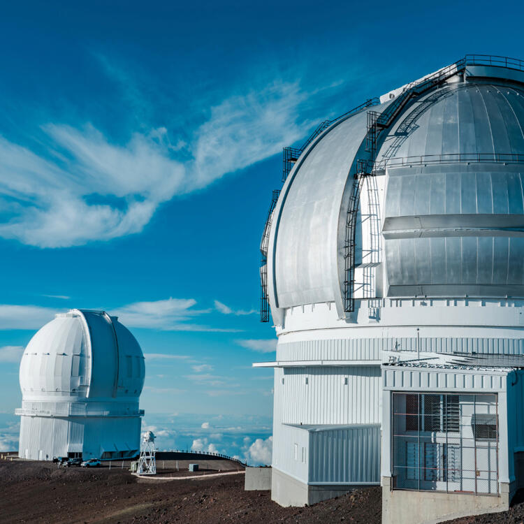 Observatorien auf dem Gipfel des Mauna Kea unter einem klaren blauen Himmel, umgeben von einer kargen vulkanischen Landschaft