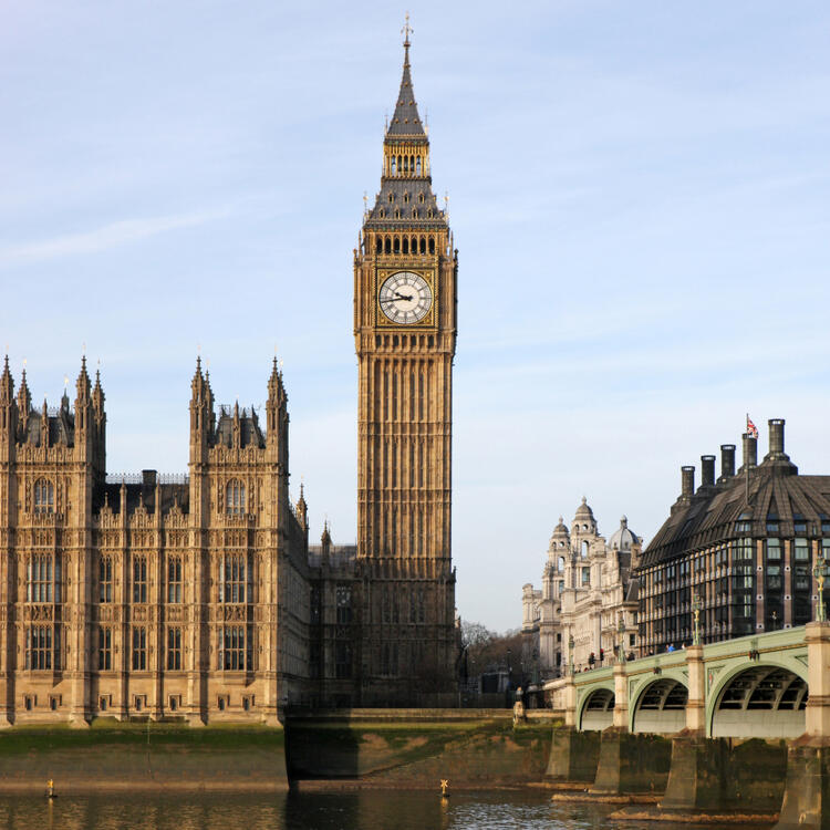 Big Ben in London im Sonnenlicht mit der Westminster Bridge im Vordergrund.