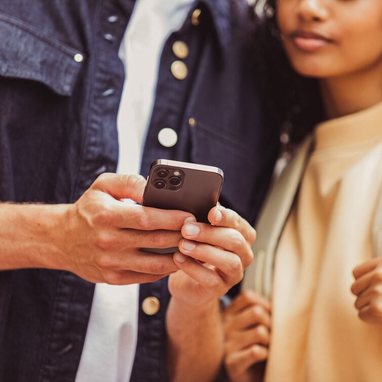 Ein Paar schaut auf ein Handy, dass sie in der hand hat. 