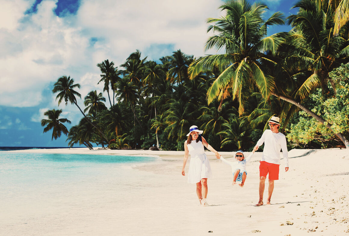 Ein Paar mit Kind geht am Palmenstrand spazieren