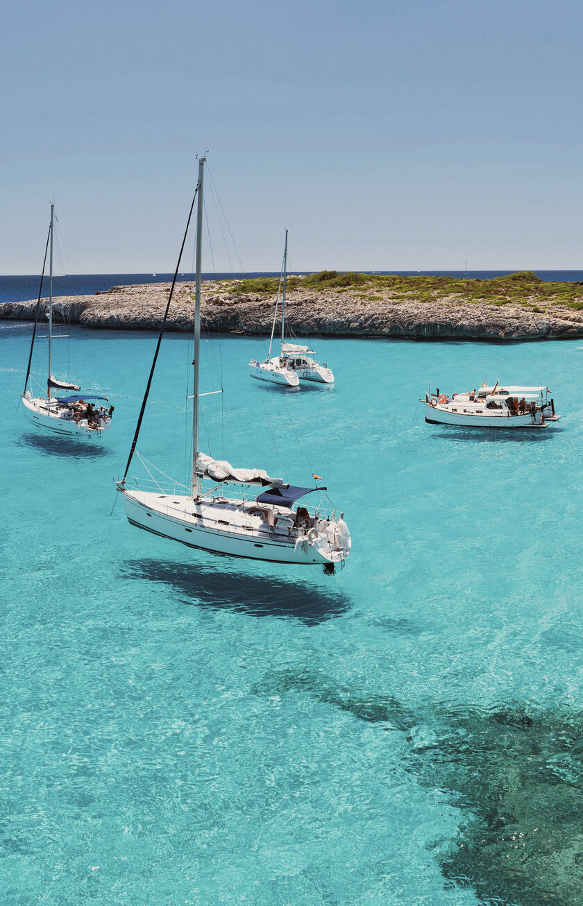Eine türkisblaue Bucht, typisch für Mallorca, mit einigen weißen Segelbooten