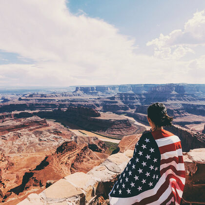 Frau mit USA Flagge steht am Grand Canyon