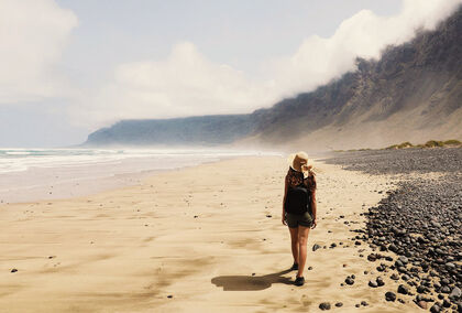 Eine Frau spaziert am Strand auf Lanzarote