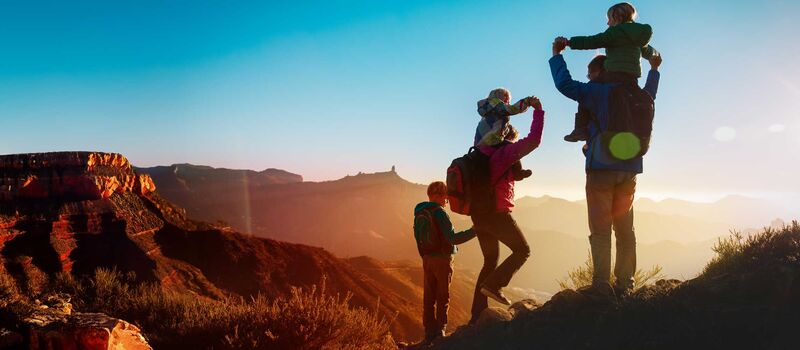 Eine Familie steht bei Sonnenuntergang am Grand Canyon