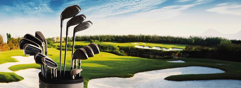 Golfplatz mit Golfbag und Schläger im Vordergrund.