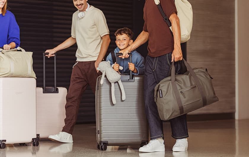 Familie mit Kind laufend am Flughafen mit Koffern