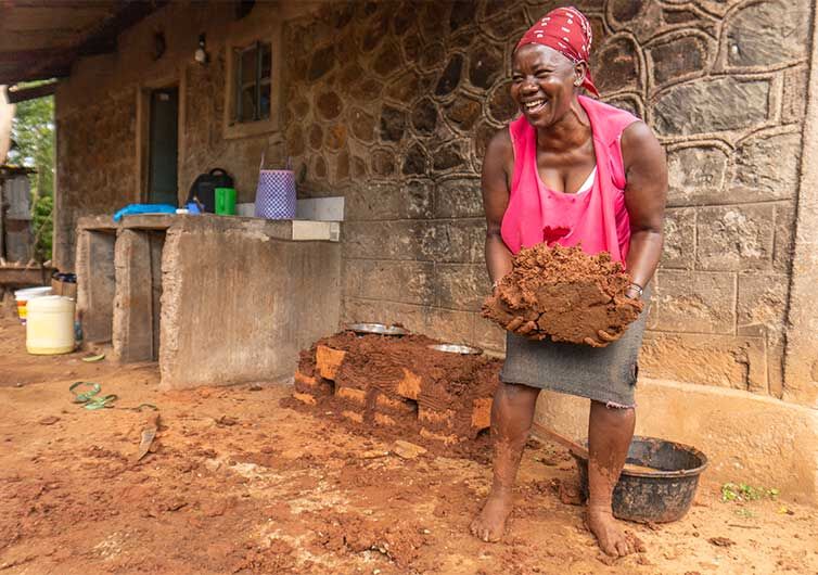 Projekt Spargemeinschaften Eine kenyanische Frau baut eine Kochstelle uas Ziegeln und Lehm