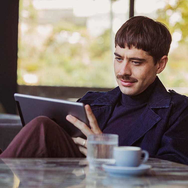 Ein Mann sitzt in der Lounge und schaut auf sein Tablet