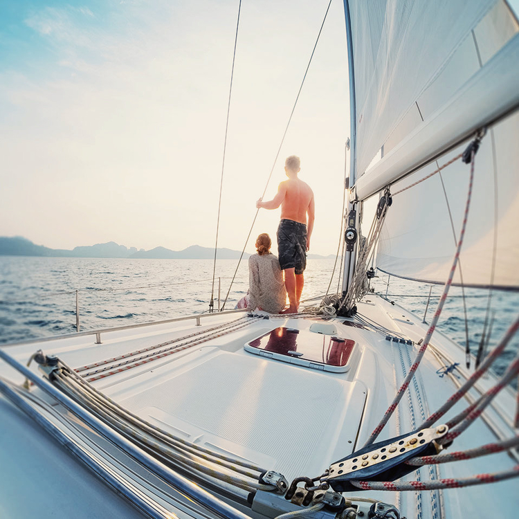 Junge Paar entspannend auf Segelboot Deck im offenen Meer bei Sonnenuntergang