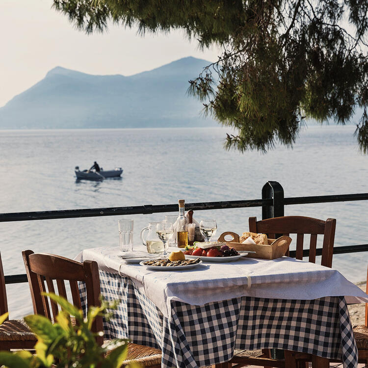 Mittagessen in einem Taverne mit Blick auf das Meer und die Insel, Griechenland