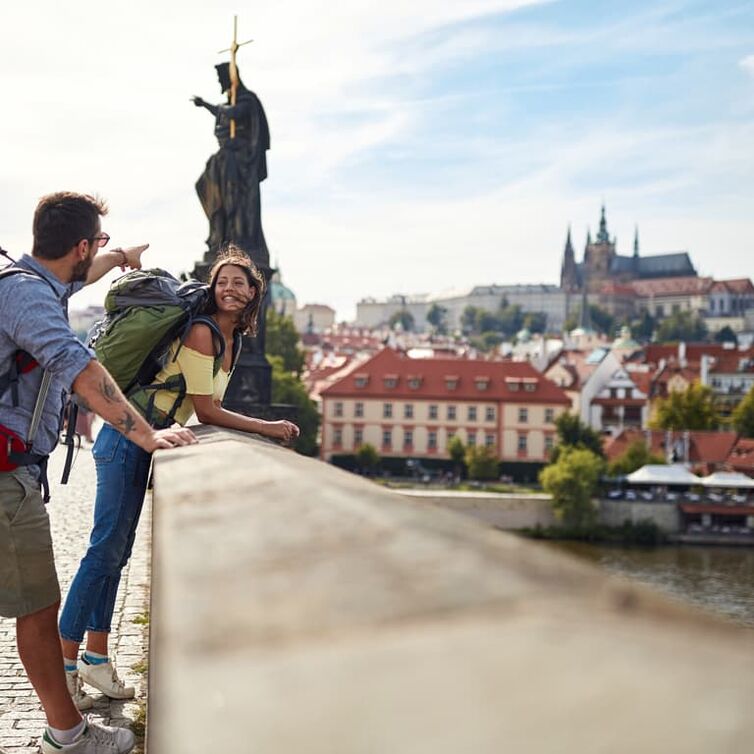 Paar blickt von der Karlsbrücke auf Prag.