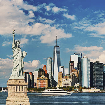 Freiheitsstatue Liberty und New York City Skyline in einem sonnigen Tag, blauer Himmel und herannahenden weißen Wolken