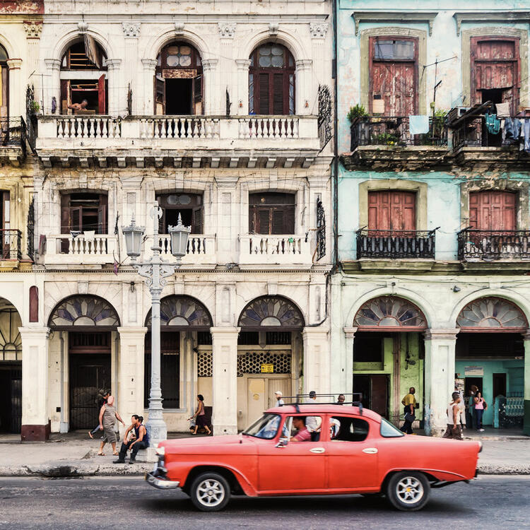 Authentischer blick auf eine straße der altstadt von havanna mit alten gebäuden und Oldtimer rotes Auto