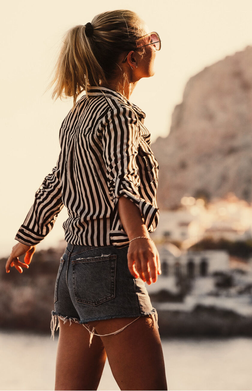 Mujer paseando por un paseo marítimo al atardecer