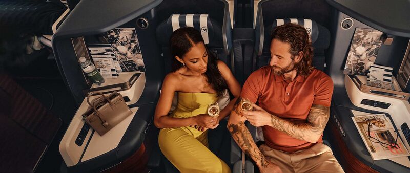 Una pareja disfruta de una copa en los asientos Prime de Condor en clase Business