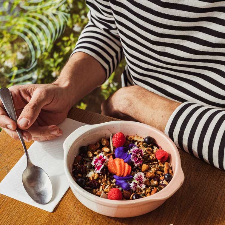 Hombre con una camiseta a rayas negras y blancas con un plato de muesli con frutas