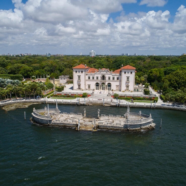Vista aérea del Museo y Jardines Vizcaya de Miami, que muestra la arquitectura clásica y la ubicación frente al mar con una estructura de barcazas de piedra