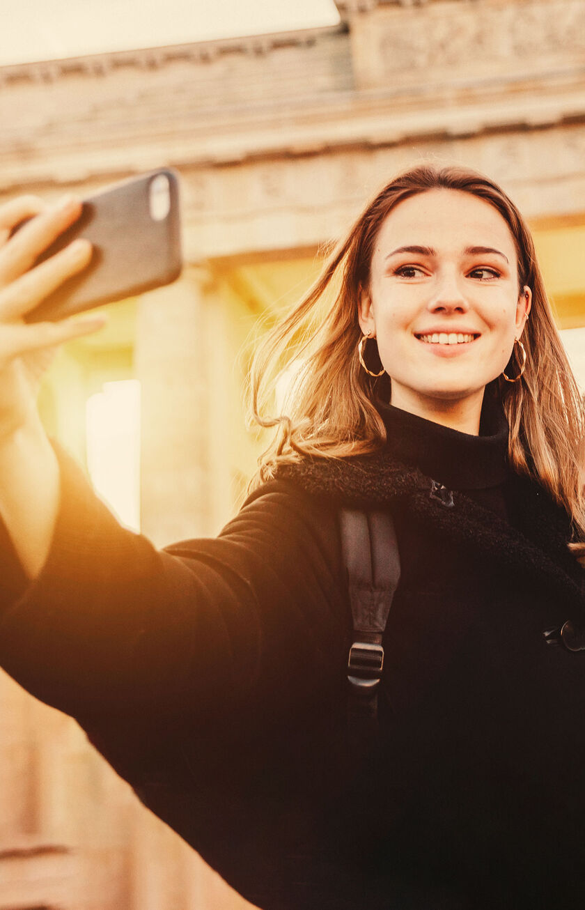 Mujer joven haciendo un selfie antes la Piuerta de Brandenburgo, en Berlín
