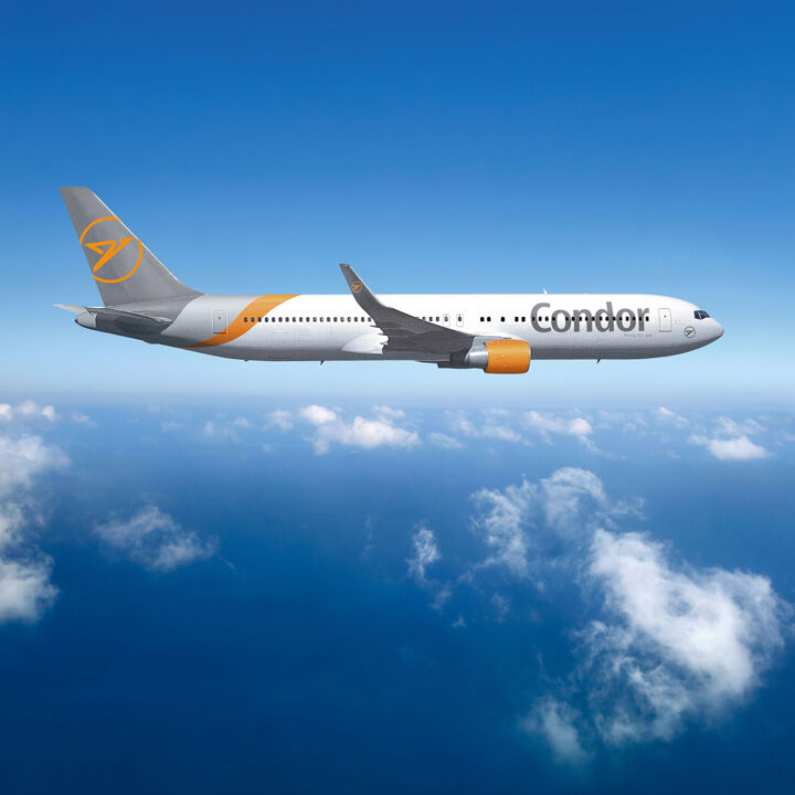 Un avión Boeing 767 con la marca Condor vuela contra un cielo azul