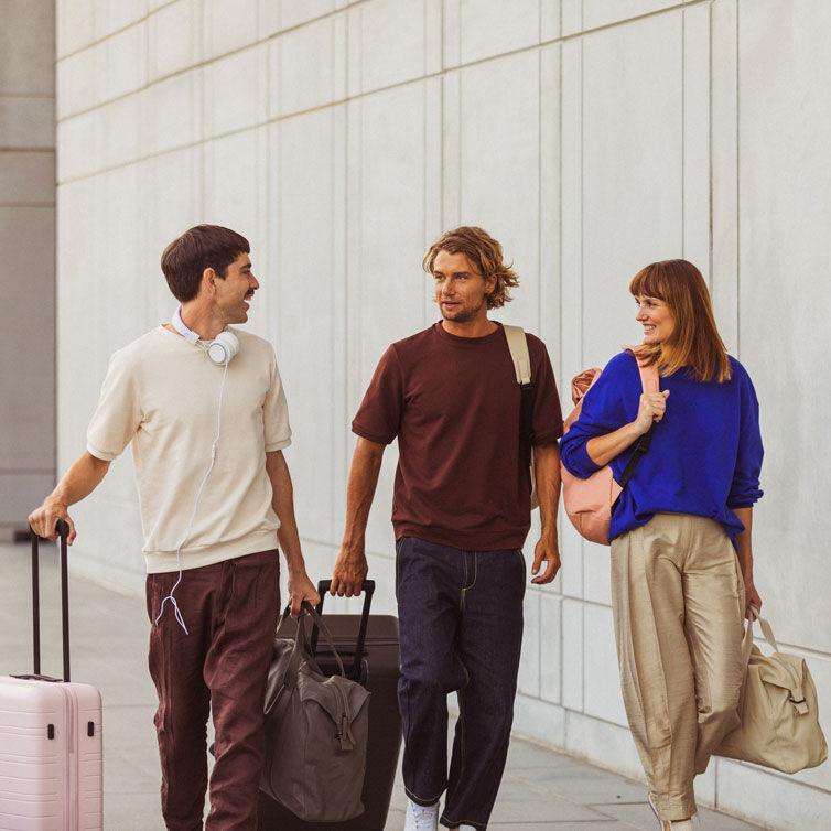 Dos hombres y una mujer andando con sus maletas en un aeropuerto