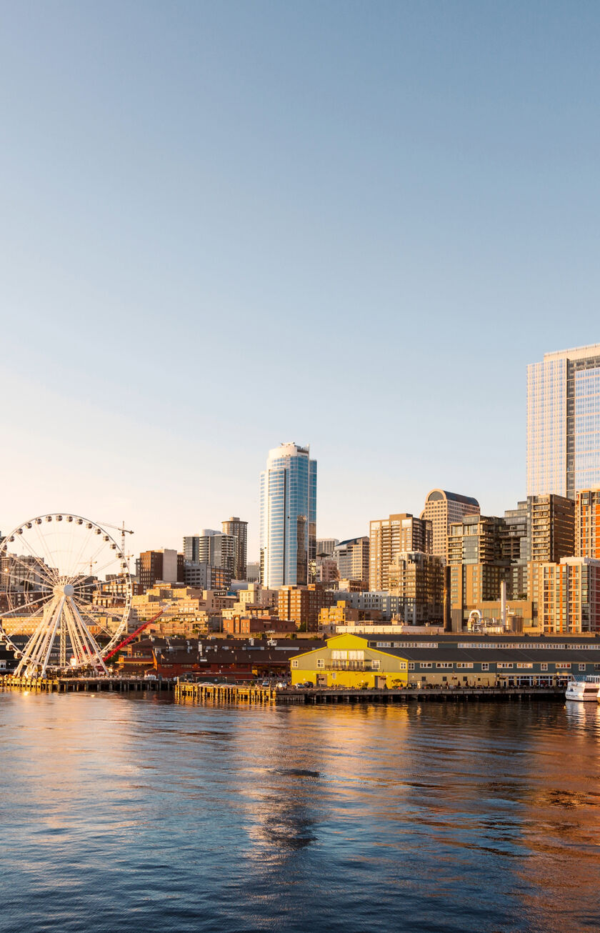 Horizonte de Seattle al atardecer con la noria, rascacielos y el reflejo dorado sobre el agua