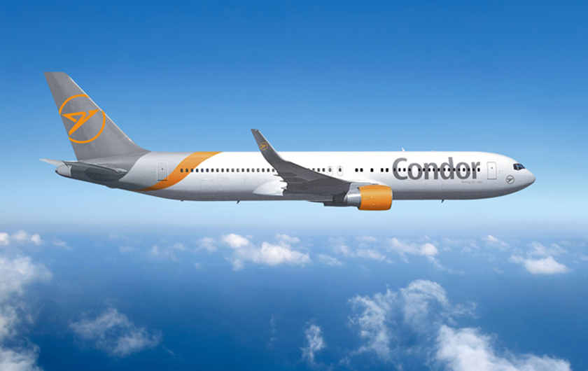 Un avión Boeing 767 con la marca Condor vuela contra un cielo azul