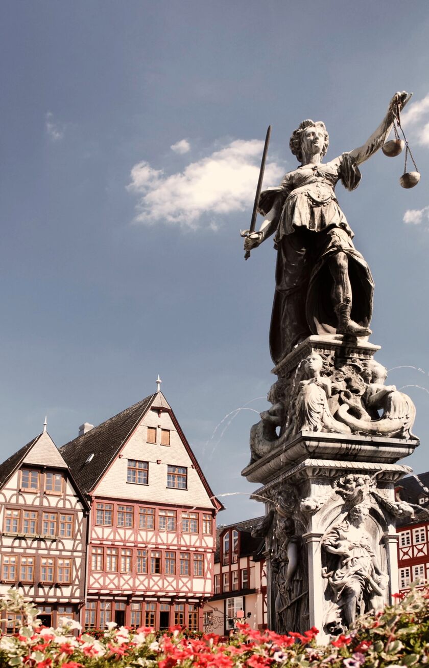 a womens statue as a fountain surrounded by half-timbered houses