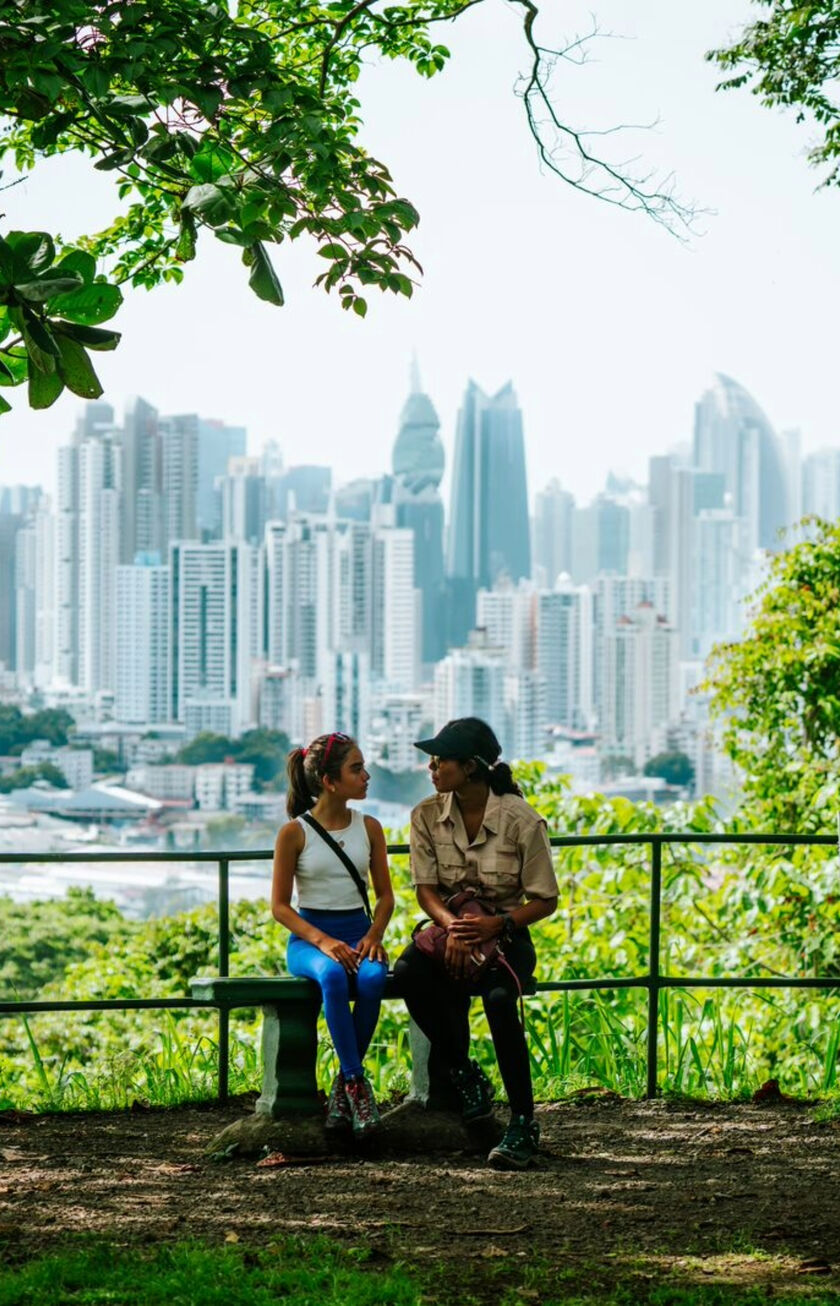 Two people sitting on a bench in a park in Panama City