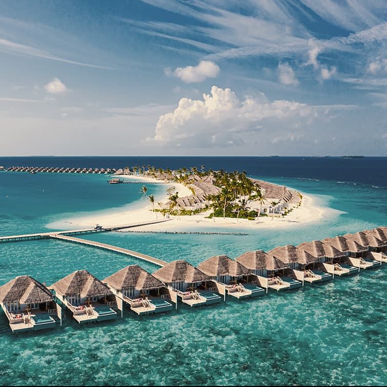 Water bungalow in a row connected by a wooden jetty to a small island in the Indian Ocean