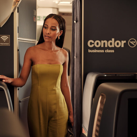 A woman enjoying champagne and a magazine on bord of Condor's business Class