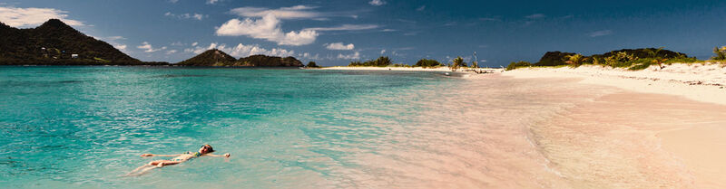 A beautiful beach and a woman swimming in the sea