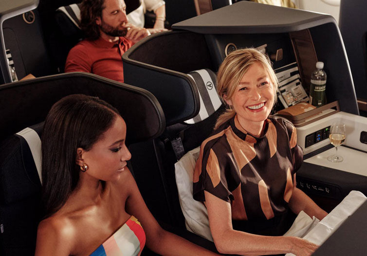Two women are sitting on a plane in business class.