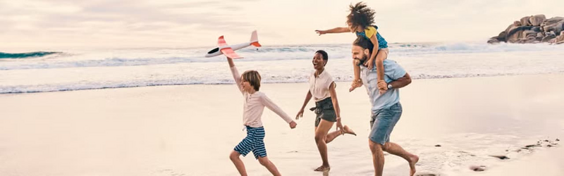 A family of four is running and playing on the beach