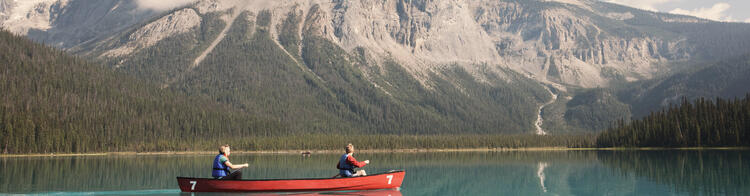 Des gens font du canoë sur un lac, avec des montagnes enneigées en arrière-plan