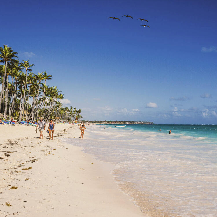 Des vacanciers se promènent sur une plage de sable blanc