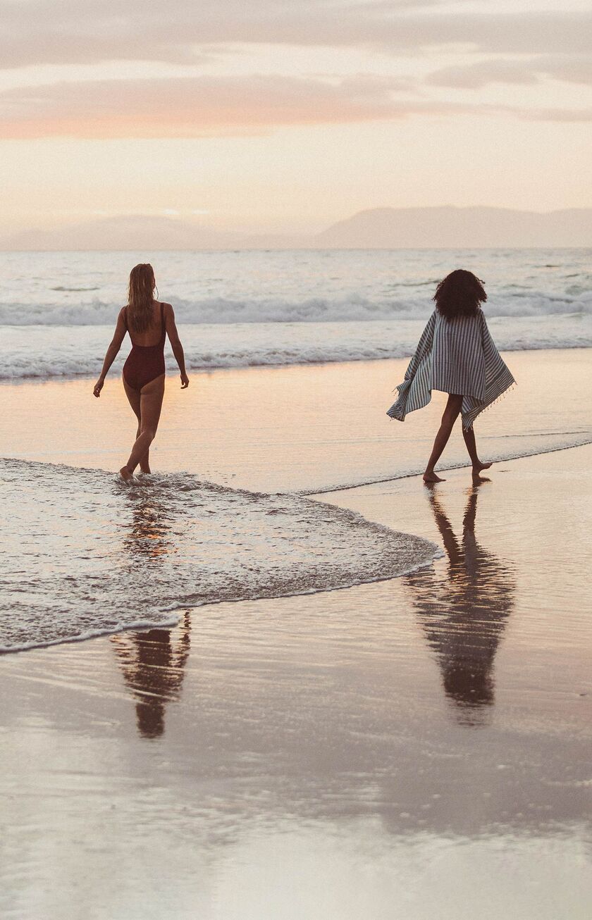 Femmes se promenant sur la plage au coucher du soleil
